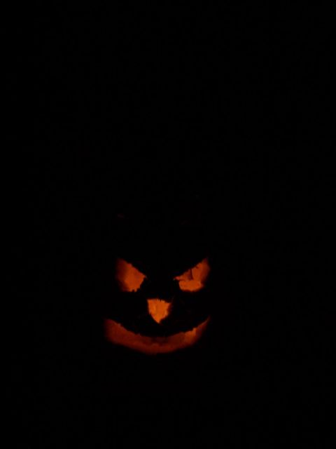1990 Ford Bronco - A carved pumpkin with a menacing face glows eerily in the darkness.