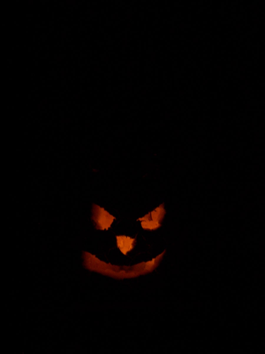 carved pumpkin with a spooky face glowing in the dark