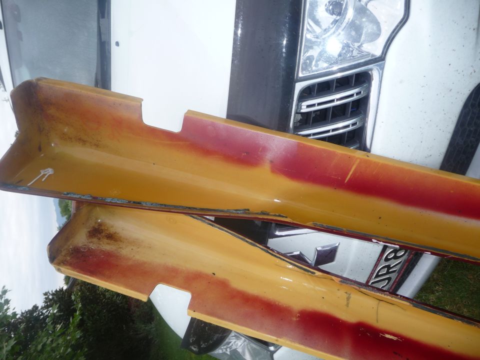 yellow and red side skirts, one on top of the other, with a vehicle grille visible behind them