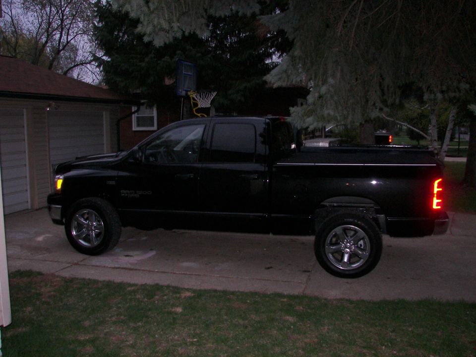 Black pickup truck parked in driveway next to a house