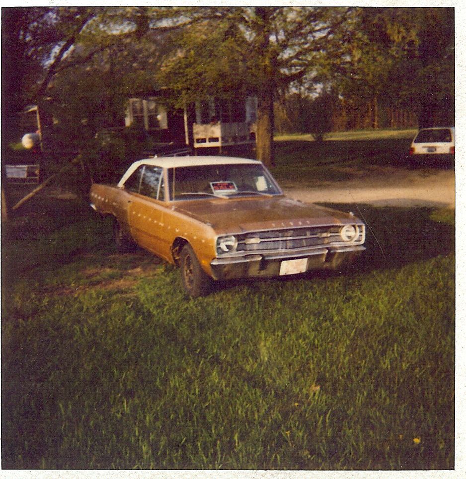 Gold 1967 Dodge Dart with white roof parked in grassy yard, house and another car in background