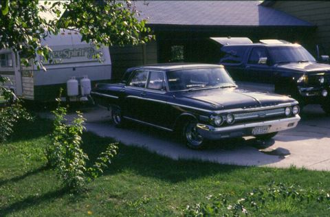 1988 Ford Bronco - A dark blue 1962 Mercury sedan is parked in a driveway, with a trailer and a pickup truck also visible.