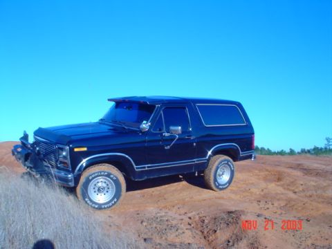1986 Ford Bronco - This 1986 Ford Bronco is parked on a dirt embankment with a clear blue sky above.
