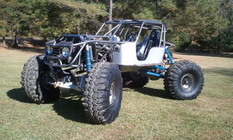 1967 Ford Mustang - Custom tube-chassis rock crawler buggy with silver aluminum panels, blue suspension links, coilover shocks and oversized mud tires on a law…