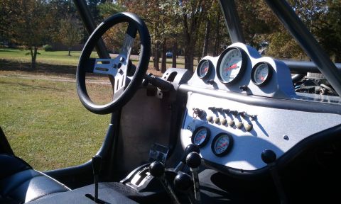 1967 Ford Mustang - The interior of a custom buggy features a roll cage, multiple gauges, and a shifter.