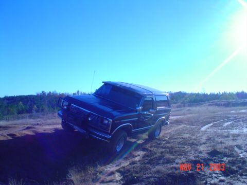 1986 Ford Bronco - A black Ford Bronco is seen off-road on a sunny day.