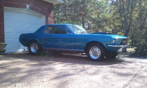 1967 Ford Mustang - 1967 Ford Mustang coupe with custom hood scoop and wheels parked outside a garage.