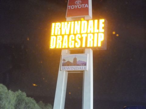 2003 Ford Crown Victoria - Lit pylon sign reading IRWINDALE DRAGSTRIP topped by a Toyota logo, photographed after dark
