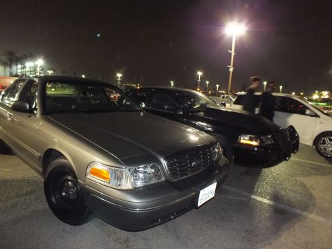 2003 Ford Crown Victoria - Gray Crown Victoria on black steel wheels parked front-first beside a black sedan under lot lights