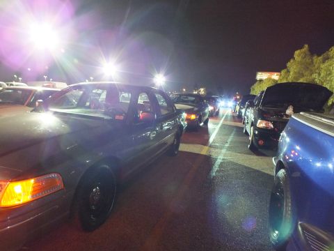 2003 Ford Crown Victoria - Crown Victoria showing red upholstery beside other vehicles in a glaring night lot lineup