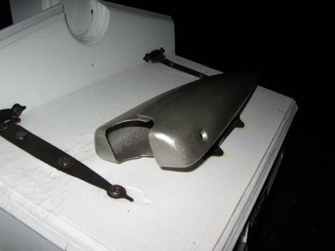 1994 Ford Bronco - A metallic component with visible hinges rests on a white surface.