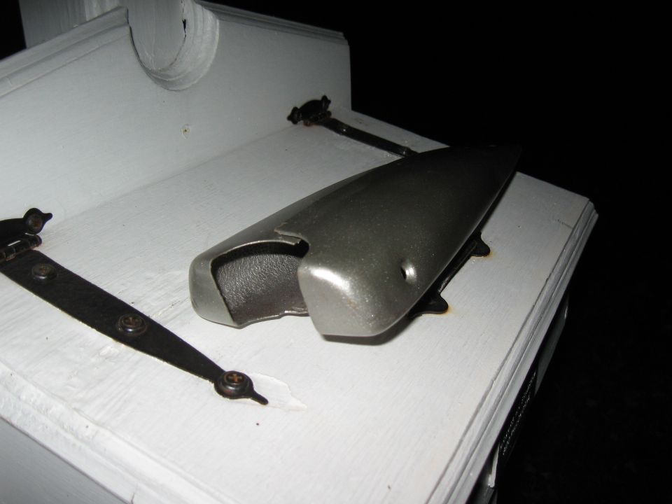Metal part with open cavity and hinges on white surface