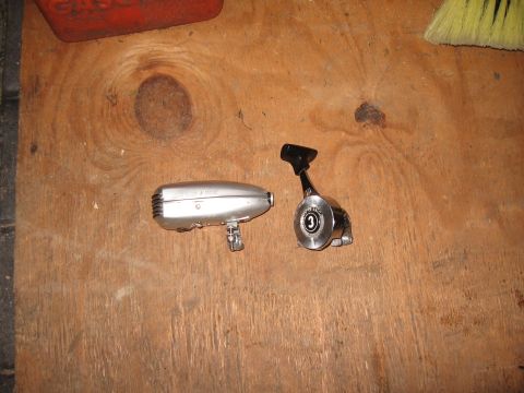 1994 Ford Bronco - A silver fishing reel body and a chrome reel handle with a '3' are laid out on a wooden surface.