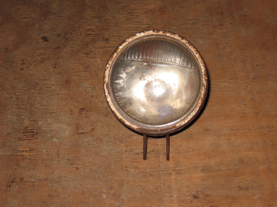 Round headlight with a rusty bezel and ribbed glass lens