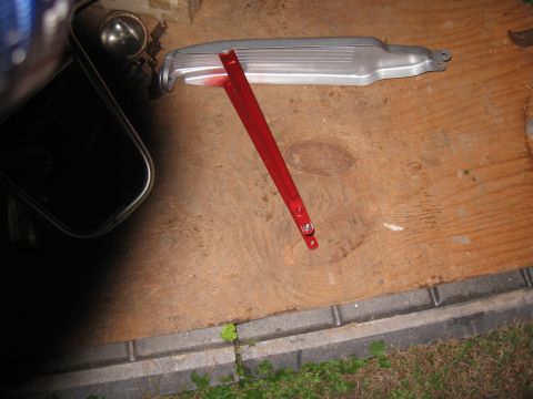 1994 Ford Bronco - A red bracket and a silver air intake part are laid out on a wooden surface.