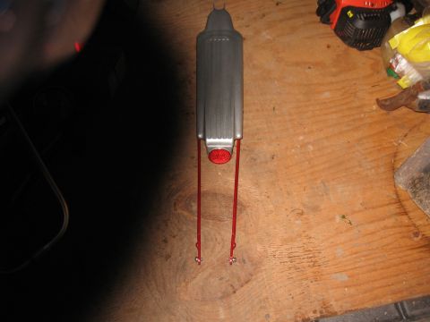 1994 Ford Bronco - A close-up view of an exhaust pipe with red wire hangers, resting on a wooden surface.