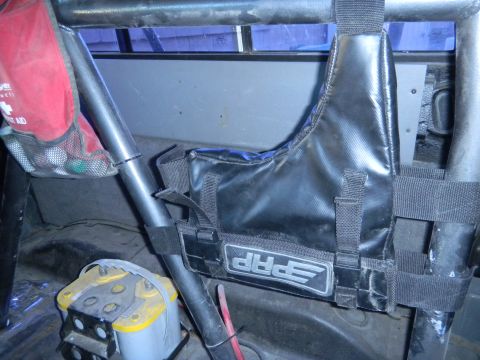 1997 Ford Ranger - The interior of a vehicle shows a roll cage, a yellow battery, and a black PRP storage bag attached to the cage.
