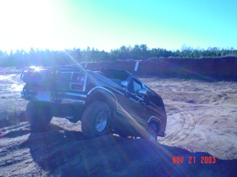 1986 Ford Bronco - 1986 Ford Bronco navigating sandy terrain under a clear blue sky.
