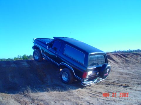 1986 Ford Bronco - This 1986 Ford Bronco is shown off-road on a sandy incline under a clear blue sky.
