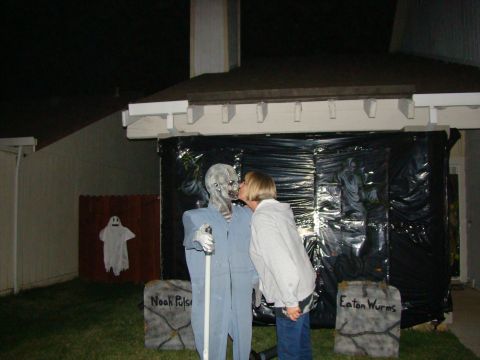 1989 Ford Bronco - A Halloween scene features a woman kissing a zombie prop, with tombstone decorations in the foreground.