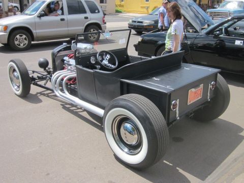 1991 Ford LTD Crown Victoria - A black hot rod pickup truck with whitewall tires and exposed exhaust pipes is parked at an outdoor car show.