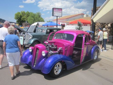 1991 Ford LTD Crown Victoria - A custom hot rod with a two-tone pink and purple paint scheme is displayed at an outdoor car show.
