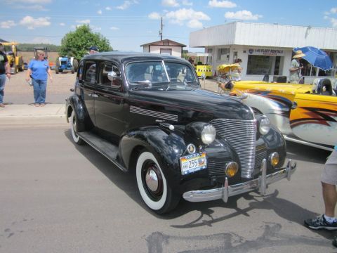 1991 Ford LTD Crown Victoria - A vintage black sedan is displayed at an outdoor car show with other vehicles and spectators.