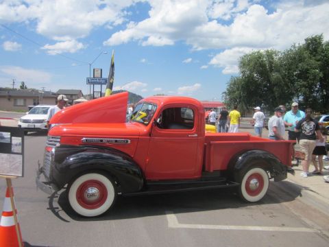 1991 Ford LTD Crown Victoria - A classic red 1940s GMC pickup truck is displayed with its hood open at an outdoor car show.