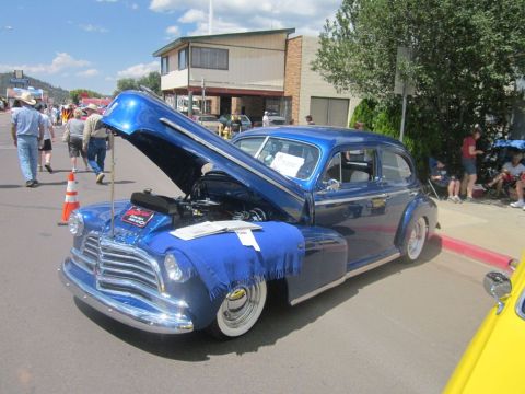 1991 Ford LTD Crown Victoria - A classic blue sedan is displayed with its hood open at an outdoor car show event.