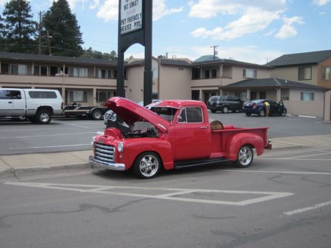 1991 Ford LTD Crown Victoria - A red pickup truck is parked with its hood open in front of a motel.
