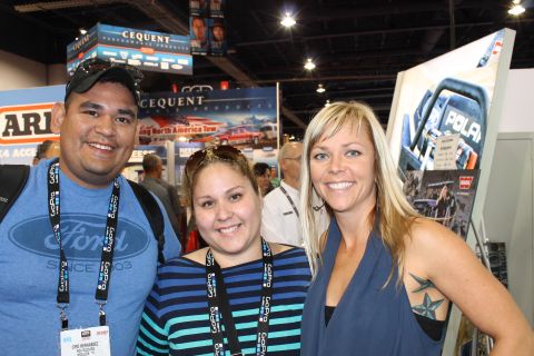 1990 Ford Bronco - Attendees pose for a photo at an event with various brand advertisements in the background.