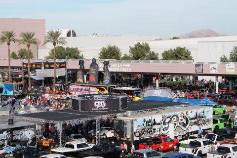 1990 Ford Bronco - A busy outdoor car show with many vehicles and promotional displays under a clear sky.