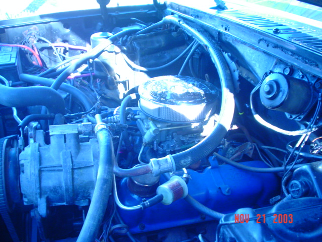 Fire-damaged V8 engine bay with blue valve covers and chrome air cleaner