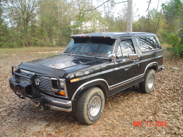 Black Ford Bronco SUV with brush guard and winch parked on leaves