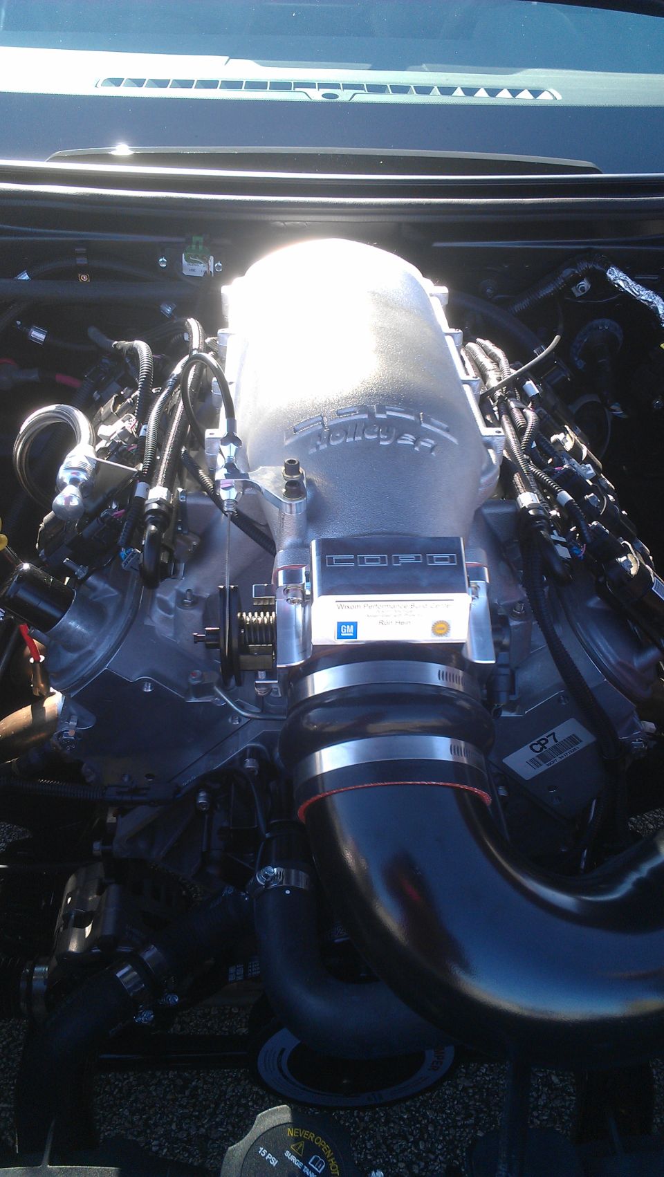 Close-up of a car engine with a large silver Holley intake manifold and black hoses