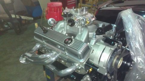1973 Chevrolet Camaro - A V8 engine with chrome valve covers and headers is shown in a workshop setting.
