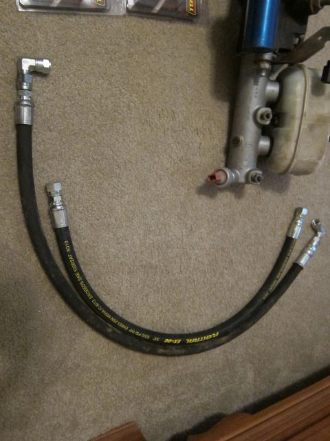 1979 Ford Bronco - Close-up of a brake master cylinder and hydraulic hoses laid out on a carpeted surface.