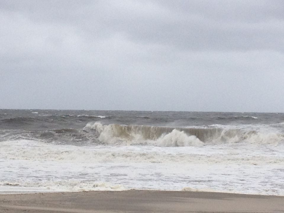 choppy ocean waves crashing on a beach under a cloudy sky