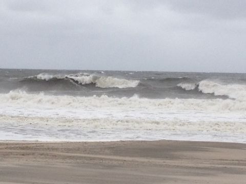 1990 Ford Bronco - Rough ocean waves batter a beach on a cloudy day.