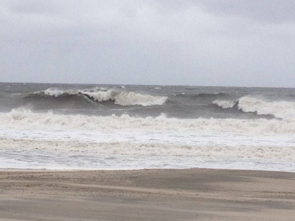 Ocean waves crashing on a sandy beach under an overcast sky