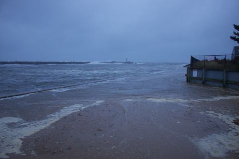 1990 Ford Bronco - A road is submerged by floodwaters from the ocean under a cloudy sky.