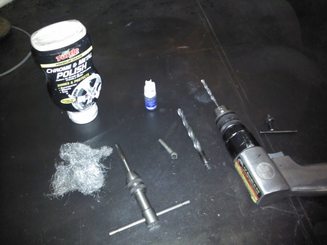 Drill, drill bits, wire wool, polish, and a tap tool laid out on a dark surface