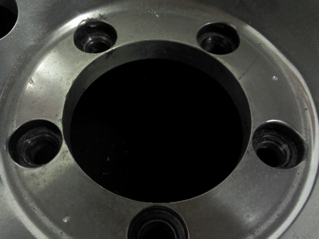 Close-up of a silver wheel hub with five lug nut holes and a black center