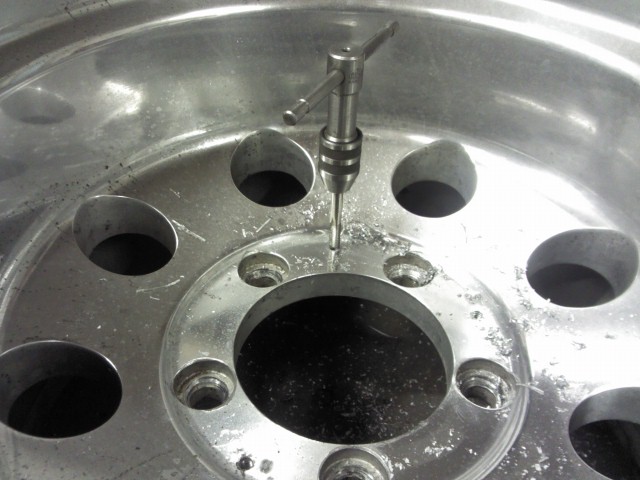 Tap handle threading a lug hole on a metal wheel