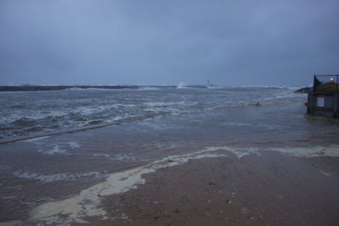 1990 Ford Bronco - Stormy weather causes flooding on a beach with a breakwater in the distance.