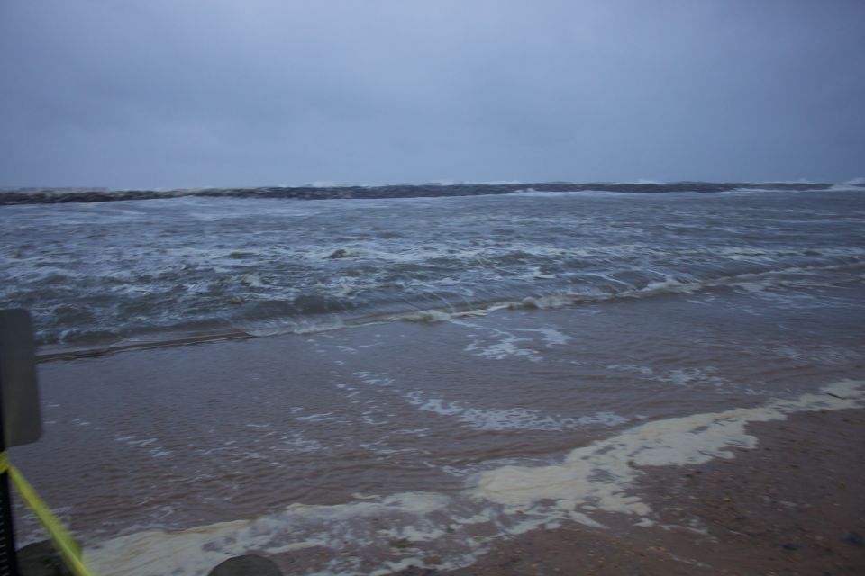 choppy ocean waves crashing on a beach under a cloudy sky