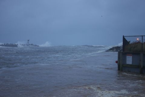 1990 Ford Bronco - The sea is rough with large waves and debris, indicating a storm or significant weather event.
