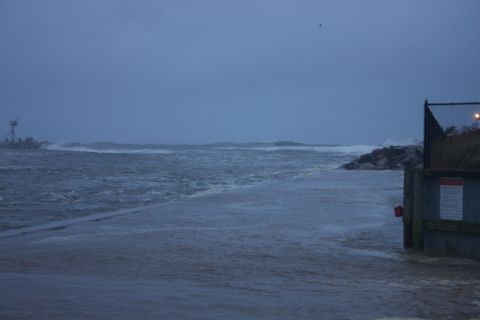 1990 Ford Bronco - A powerful storm churns the ocean, with waves breaking over rocks and a flooded walkway.