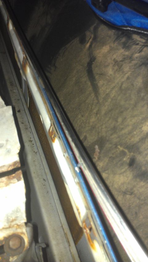 1973 Chevrolet Camaro - Close-up of weathered chrome trim, showing signs of rust and a blue reflection.