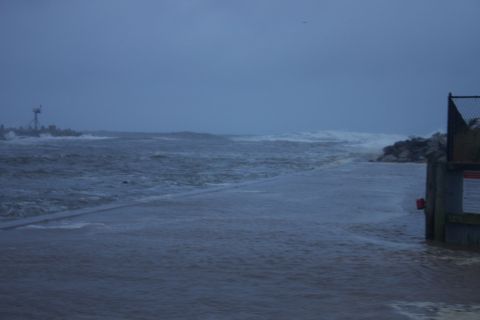 1990 Ford Bronco - The ocean is rough with large waves during a storm, with a pier visible on the right.